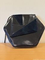 Front view of hexagon black leather purse with geometric flap
