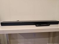 Front view of Bose SoundTouch 300 soundbar with remote control on table