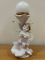 Full view of porcelain cherub candleholder with candle inserted