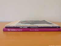 Stacked view of three hardcover art books showing spines and thickness