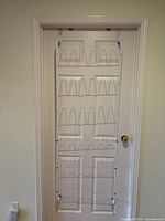 Full front view of white over-the-door shoe rack mounted on door