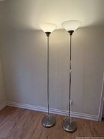 Both lamps standing side by side illuminated to show height and finish
