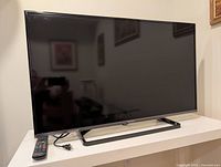 Front view of Panasonic TC-42AS630U TV on stand with remote and power cord visible