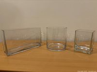 All three clear glass vases upright on tabletop