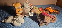 Group of four standard Beanie Babies and two sealed minis on quilted surface