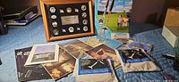All items displayed on table including framed pin set, rocket kit, sealed packs, patch and photos