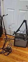 Fender amp, tubular guitar stand, coiled cable on floor