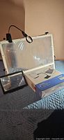 Overview of all magnifiers including boxed Magnipros lamp, large screen magnifier and handheld page magnifier