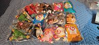 Group of thirteen sealed Teenie Beanie Baby packages on quilted surface