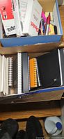 Top view of two boxes showing notebooks and writing supplies