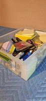 Bin filled with assorted sticky notes, pens, tape