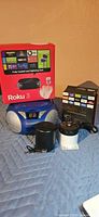 Group shot showing Roku 3 box, Fire TV Stick box, Magnavox boombox, portable speaker