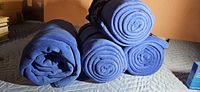 Stack of five rolled blue fleece blankets showing rolled ends