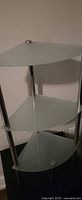 Full view of three-shelf corner unit showing frosted glass shelves and chrome supports
