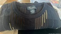 Label showing Tosani Canada brand and size XL/EG tag on folded sweater