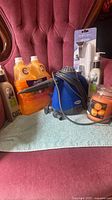 All items arranged on chair: Swiffer cleaners, Cucina soaps, blue steam cleaner, Bathscape TP holder package, orange candle