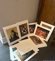 Array of standing and stacked art prints showing portraits and scenes