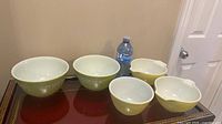 Five green Pyrex mixing bowls on table
