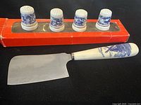 Cheese cutter and four thimbles displayed in packaging