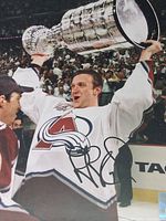 Rob Blake hoisting Stanley Cup, signature visible