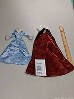 Full view of blue glitter gown and black/red cape with ruler for scale