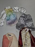 Front view of iridescent shirt, silver breeches, burgundy coat front and striped waistcoat collar visible