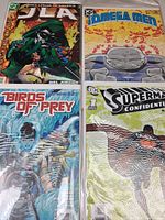 Four comics side by side in sleeves: JLA #35, Omega Men #2, Birds of Prey #20, Superman Confidential #1