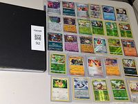 Closed black binder and array of Pokémon cards laid out