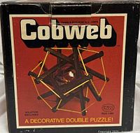 Front of Cobweb puzzle box displaying assembled wooden puzzle and branding