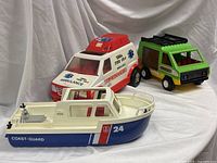 Group shot showing all three toy vehicles: ambulance truck, Coast Guard boat, green van