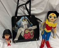 Group shot of Wonder Woman handbag, bobblehead and plush doll