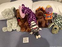 Group shot of all seven plush toys on bed