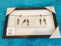 Full view of framed print with protective corner covers and MaxSold lot tag