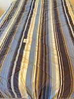 Comforter on bed showing full striped pattern
