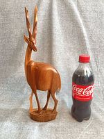 Full view of antelope figurine beside soda bottle for scale