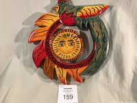 Full view of carved and painted wood plaque with sun face and bird
