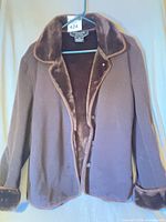 Full view of brown coat on hanger showing faux fur collar and cuffs