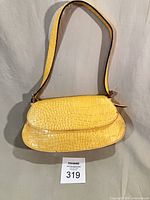 Front view of yellow faux croc baguette handbag with strap