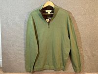 Full view of sweater on hanger showing green side and overall condition