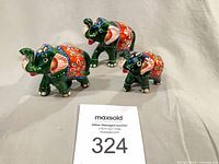 Front view of three painted elephant figurines