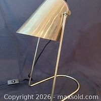 Full view of brass desk lamp showing cone shade, frame, base, and cord