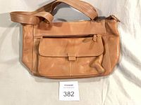 Front view showing tan leather handbag, front flap pocket, double handles, overall condition