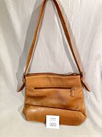 Front view of tan Tignanello leather shoulder bag with front zip pocket and wide strap