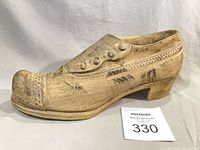 left side view of stone shoe figurine showing button detail
