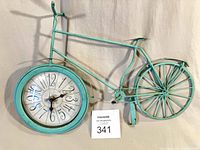 Full view of turquoise painted metal bicycle clock standing upright
