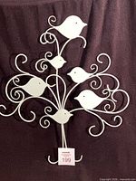Full view of white metal bird tree wall art against dark backdrop