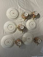 Underside view showing Royal Crown Derby backstamps on five saucers and five cups