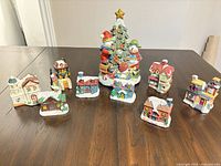 All village pieces arranged on table showing Santa figure surrounded by nine village buildings