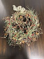 Full view of artificial Christmas wreath showing spiral design, berries, stars, bow