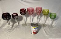 Front view of seven colour-tinted cut crystal wine glasses showing etched patterns and clear stems
